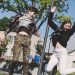 Two teenagers joyfully jumping outdoors in Šiluva, Lithuania under a bright blue sky. Captured in springtime.